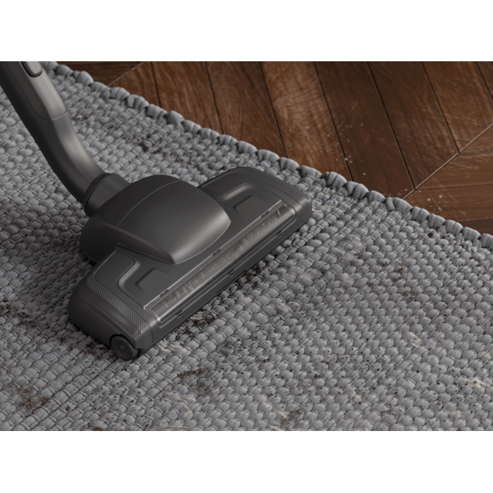 Turbo floor nozzle vacuuming dirt of a grey carpet.