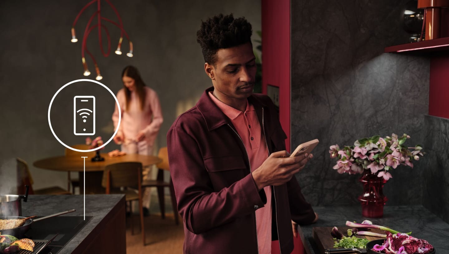 Een man kijkt in de keuken naar zijn telefoon.