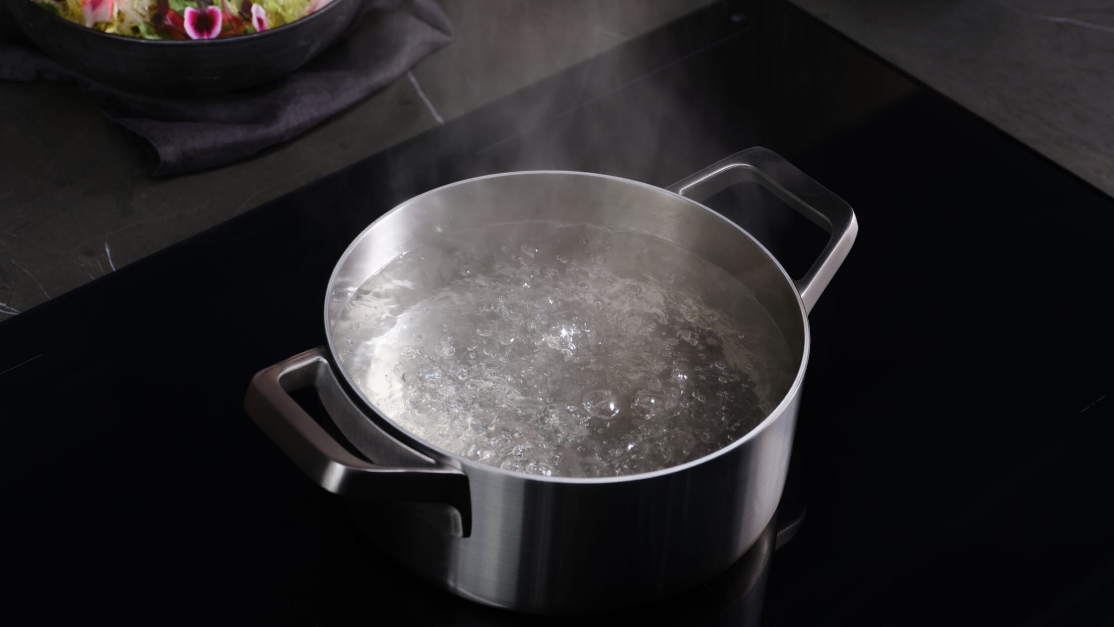 Een stoofschotel met kokend water op een inductiekookplaat.