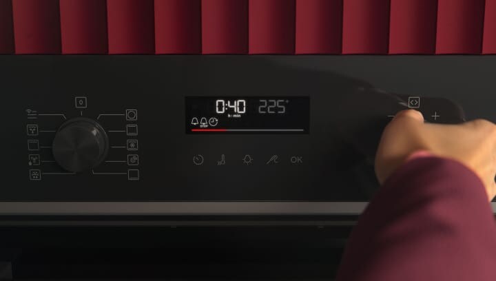 Een persoon klikt op het bedieningspaneel van een oven.