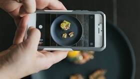 Des individus prennent en photo une assiette gastronomique parfaitement dressée