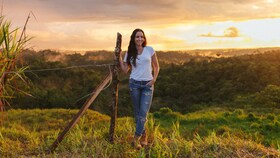 Catalina Vélez staat in een zonovergoten veld bij zonsondergang