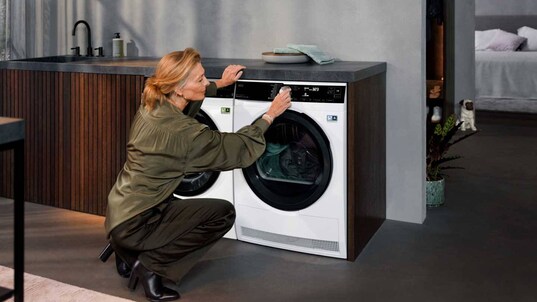 Femme qui programme un sèche-linge AEG