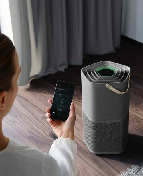 Une femme et son smartphone devant un purificateur d’air
