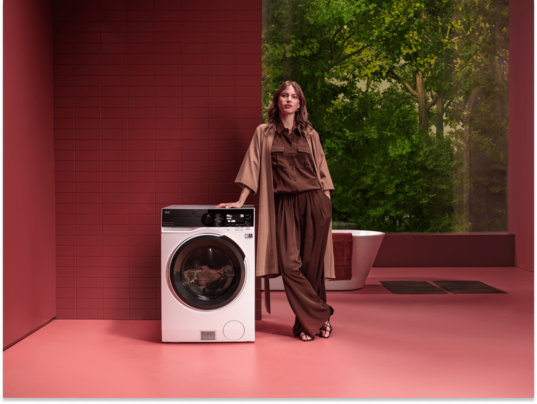 Vrouw die naast een AEG wasmachine staat.