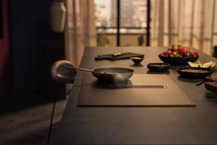 Un homme cuisine sur une plaque de cuisson dans la cuisine.