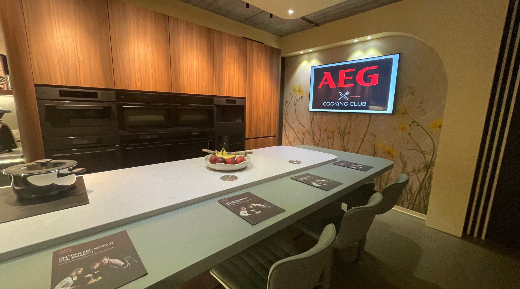 Cooking Club Aartselaar met een tafel in een keukenopstellen vol met AEG keukenapparatuur en een tv die aan staat met het logo van AEG